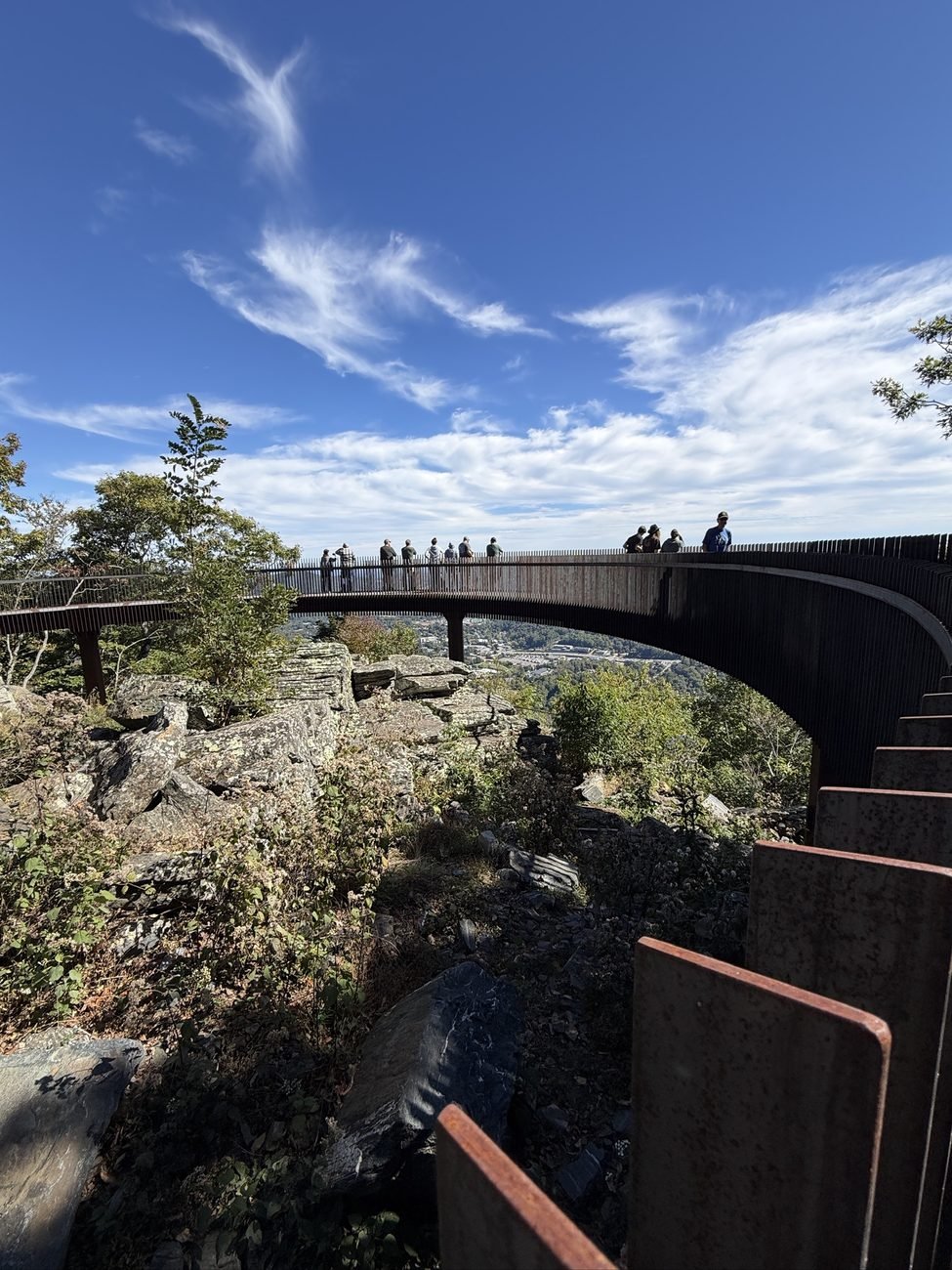 Weathered steel panels in the foreground of the Howard Knob overlook, with visitors on the curved walkway beyond